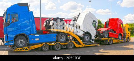 Truck carrier truck transporting three brand-new trucks of red, blue and white color, panorama image Stock Photo