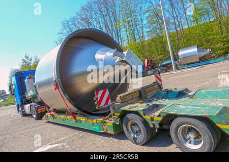 AACHEN, NRW, GERMANY - April 18, 2019: Heavy haulage of a big stainless steel container on a low-loader trailer truck, parking at a truck stop Stock Photo