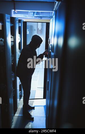 Beware of thieves in the night. a hacker using a digital tablet in a server room. Stock Photo