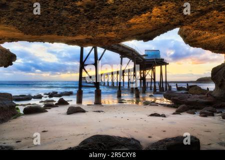 Sea cave on Middle Camp beach of Catherine hill bay under historic timber jetty in Australia. Stock Photo