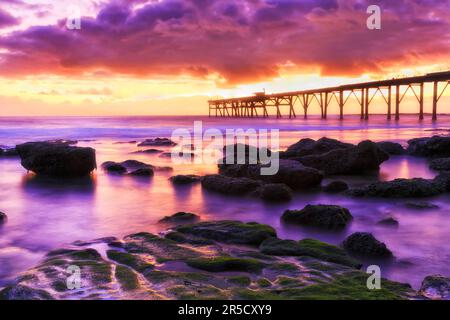 Seascape of Middle camp beach at Catherine Hill bay in Australia on Pacific coast with historic timber jetty at sunrise. Stock Photo
