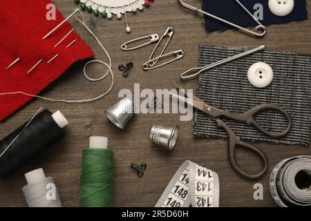 Flat lay composition with thimbles and different sewing tools on wooden table Stock Photo