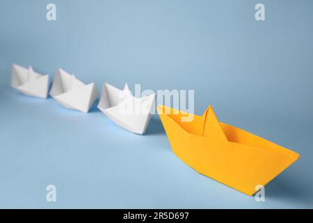 Group of paper boats following yellow one on light blue background. Leadership concept Stock Photo