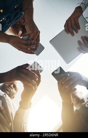 Wireless technology leads the way forward. Closeup shot of a group of businesspeople using digital devices in synchronicity in an office. Stock Photo