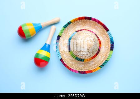 Colorful maracas and sombrero hat on light blue background, flat lay. Musical instrument Stock Photo