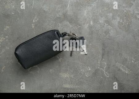 Leather case with keys on grey textured table, top view. Space for text Stock Photo