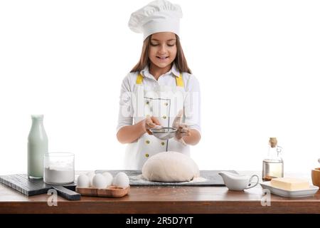 Little baker sprinkling flour onto dough on white background Stock Photo