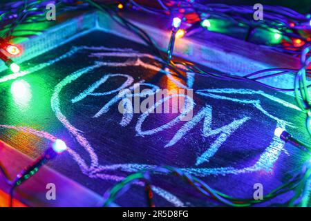 Chalkboard with word PROM and glowing lights on dark background, closeup Stock Photo