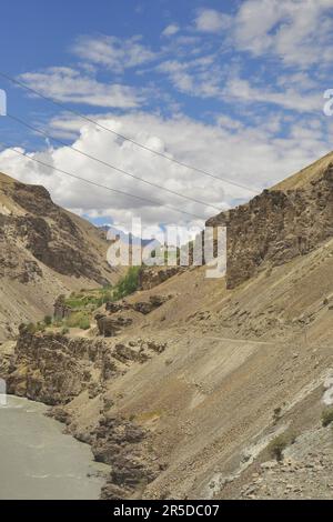 Beautiful view of flowing river in between  rocky mountains with clouds in the sky on the way of Padum, Zanskar, Ladakh, INDIA Stock Photo