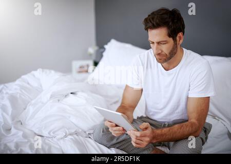 Looking for remedies for insomnia. a handsome middle aged man using his digital tablet while relaxing in his bedroom. Stock Photo