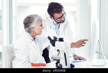 The old and new generation of doctors working together. two focused scientist working together on a computer inside of a laboratory. Stock Photo