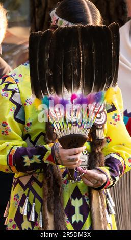 Female Native American holding a feather fan and wearing a jingle dress at a pow-wow in Evans, Georgia. Stock Photo