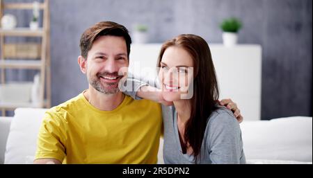 Portrait Of Happy Couple Sitting On Couch Stock Photo