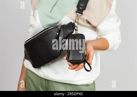 Small Leather Case for for Electronic Cigarette Attached to the Black Genuine Leather Fanny Pack Strap. No Face Female Model over Gray Background, Stu Stock Photo