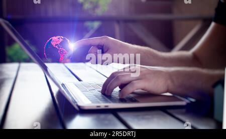 Man using laptop with digital sphere hologram on blurry background. Technology Stock Photo