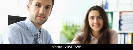 Businessman and businesswoman are sitting at table in office with documents Stock Photo