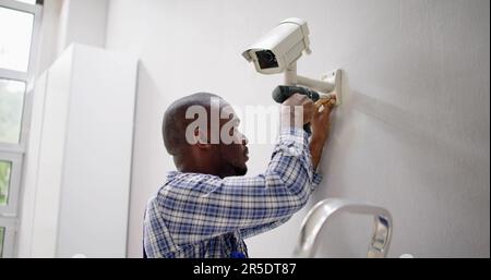 Close-up Of Technician Adjusting CCTV Camera On Wall Stock Photo
