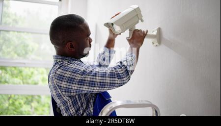 Close-up Of Technician Adjusting CCTV Camera On Wall Stock Photo
