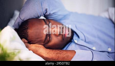 Young African Man Suffering From Fever Lying On Bed Stock Photo