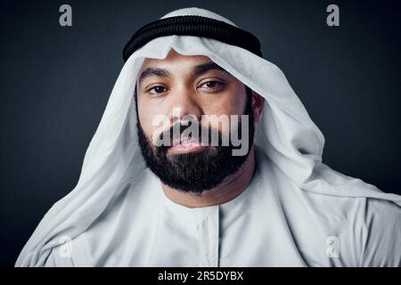 Ready for business. Studio shot of a young man dressed in Islamic traditional clothing posing against a dark background. Stock Photo