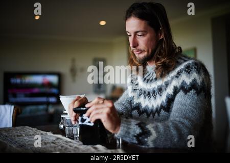 Coffee for one. a young man preparing coffee in his kitchen. Stock Photo