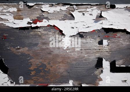 Close up of white weathered paint peeling off the hull of a fishing boat. Stock Photo