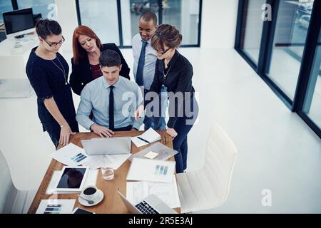 Taking charge of business together. group of businesspeople using a laptop together during a meeting in an office. Stock Photo