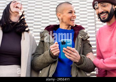 three young friends laughing using a phone Stock Photo