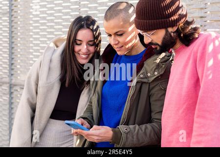 three young friends enjoying using phone together Stock Photo