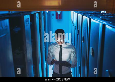 This is running much better. a young IT specialist standing alone in the server room and using a digital tablet. Stock Photo