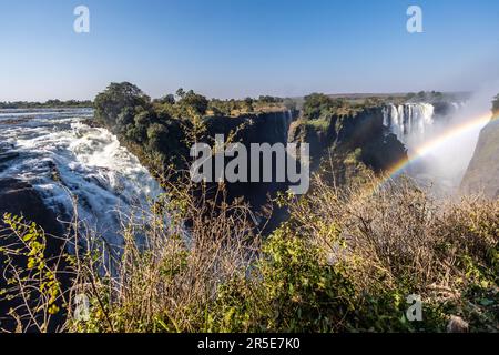 Exterior shot of a rainbow in front of Victoria Falls, Zimbabwe, on an afternoon. Stock Photo
