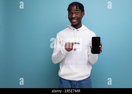 young dark-skinned brunette man holding smartphone with screen mockup Stock Photo