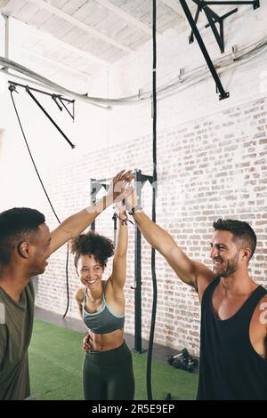 Enjoying the benefits of working out as part of a group. three sporty young people giving each other a high five. Stock Photo