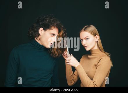 Girl scheming an evil plan of cutting off a curly hair in a man. A smart wily woman has wonderful schemes like a crook of a friend, a dark background Stock Photo