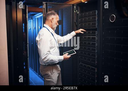 Keeping you safe from cyber security threats. a mature man using a digital tablet while working in a server room. Stock Photo