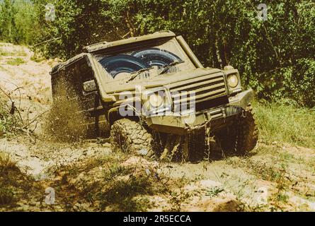 Off road sport truck between mountains landscape. 4x4 travel trekking. Jeep crashed into puddle and picked up spray of dirt. Bottom view to big Stock Photo