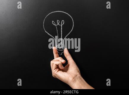 close up of hand holding lightbulb chalk drawing Stock Photo