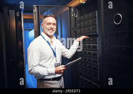 You cant spell programmer without me. a mature man using a digital tablet while working in a server room. Stock Photo