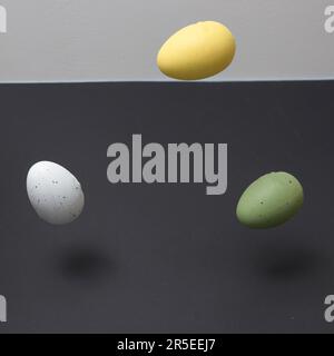 Three colored eggs levitating with copy space on a black and white background. Minimal Easter scene. Stock Photo
