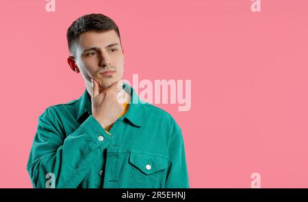 Thinking puzzled man on pink background. Guy looking for answer, copy space Stock Photo
