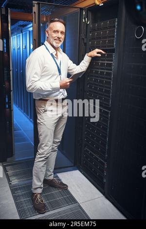 The server room is my second home. a mature man using a digital tablet while working in a server room. Stock Photo