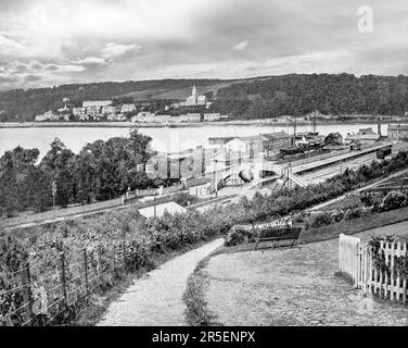 A late 19th century view of the waterfront and railway station in Monkstown, a village in County Cork, Ireland. It lies on the estuary of the River Lee, facing Great Island and looking onto Monkstown Bay. The name of the village is said to derive from an early monastic site near to where Monkstown Castle now stands, altough no archaeological evidence remains for the monastery. Stock Photo