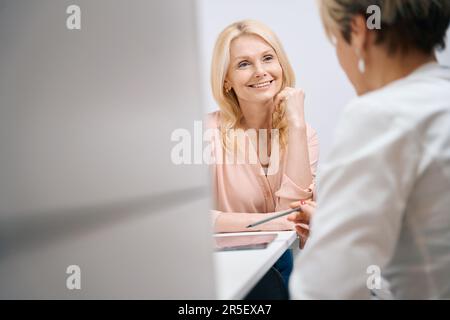 Nice woman smiling while talking to doctor in gynecologist office Stock Photo