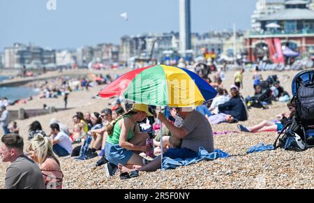 Brighton UK 3rd June 2023 - Time to get the beach umbrella out to get some shade on another hot sunny day in Brighton : Credit Simon Dack / Alamy Live News Stock Photo