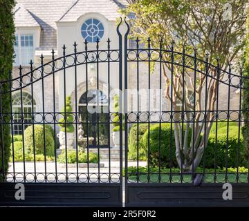 looking through black wrought iron gates at a southampton mansion Stock Photo