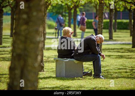 Eschede, Germany. 03rd June, 2023. A couple sits on a stone under cherry trees at the 25th anniversary memorial for the victims of the Eschede ICE accident. On June 03, 1998, after a wheel tire broke in Eschede, Lower Saxony, several carriages of an ICE train crashed into a road bridge at a speed of 200. 101 people died. Credit: Gregor Fischer/dpa/Alamy Live News Stock Photo