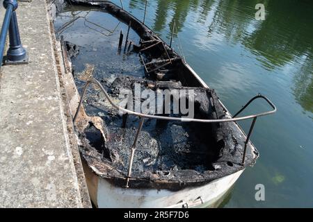 Maidenhead, UK. 3rd June, 2023. Two boats have been destroyed by fire in two separate incidents this week during the early hours of 31st May and 2nd June along the River Thames in Maidenhead, Berkshire. One of the charred wrecks remains cordoned off (pictured) and is now moored outside the riverside Chandlers Quay flats where there is a strong smell of fuel. The other boat that was destroyed by fire near to Boulter's Lock has, according to local residents, now sunk. Fortunately nobody was injured in the two fires. Thames Valley Police are reported to be making further investigations into alleg Stock Photo