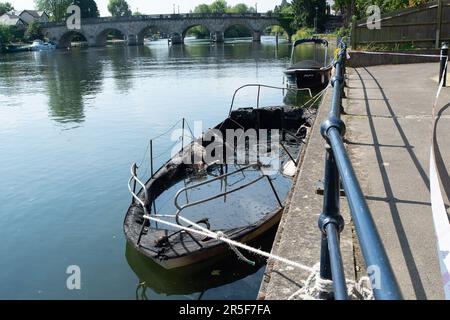 Maidenhead, UK. 3rd June, 2023. Two boats have been destroyed by fire in two separate incidents this week during the early hours of 31st May and 2nd June along the River Thames in Maidenhead, Berkshire. One of the charred wrecks remains cordoned off (pictured) and is now moored outside the riverside Chandlers Quay flats where there is a strong smell of fuel. The other boat that was destroyed by fire near to Boulter's Lock has, according to local residents, now sunk. Fortunately nobody was injured in the two fires. Thames Valley Police are reported to be making further investigations into alleg Stock Photo