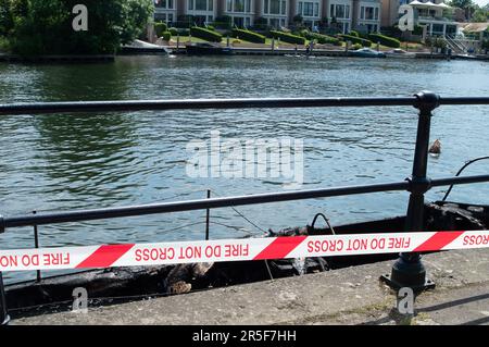 Maidenhead, UK. 3rd June, 2023. Two boats have been destroyed by fire in two separate incidents this week during the early hours of 31st May and 2nd June along the River Thames in Maidenhead, Berkshire. One of the charred wrecks remains cordoned off (pictured) and is now moored outside the riverside Chandlers Quay flats where there is a strong smell of fuel. The other boat that was destroyed by fire near to Boulter's Lock has, according to local residents, now sunk. Fortunately nobody was injured in the two fires. Thames Valley Police are reported to be making further investigations into alleg Stock Photo