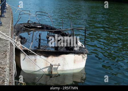 Maidenhead, UK. 3rd June, 2023. Two boats have been destroyed by fire in two separate incidents this week during the early hours of 31st May and 2nd June along the River Thames in Maidenhead, Berkshire. One of the charred wrecks remains cordoned off (pictured) and is now moored outside the riverside Chandlers Quay flats where there is a strong smell of fuel. The other boat that was destroyed by fire near to Boulter's Lock has, according to local residents, now sunk. Fortunately nobody was injured in the two fires. Thames Valley Police are reported to be making further investigations into alleg Stock Photo